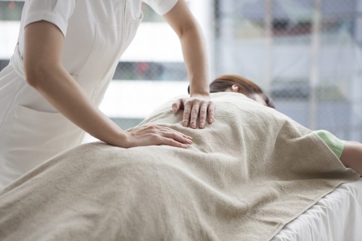Massage Tuina : pressions des mains sur le dos d'une patiente allongée